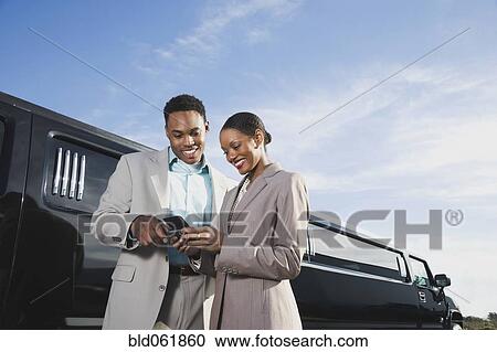 Stock Image - African businesspeople looking at cell phone. Fotosearch