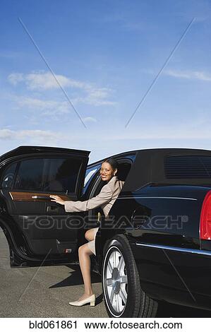 Stock Image - African businesswoman getting out of limousine. Fotosearch