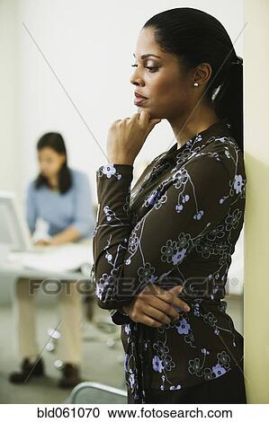 Stock Image - African businesswoman leaning against wall. Fotosearch
