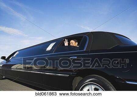 Stock Image - African businesswoman waving from limousine. Fotosearch
