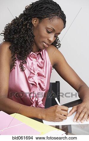 African businesswoman writing at table View Large Photo Image Picture - African businesswoman writing at table. Fotosearch
