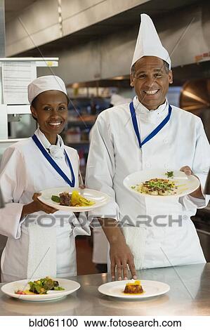 Stock Image - African chefs holding plates of food. Fotosearch