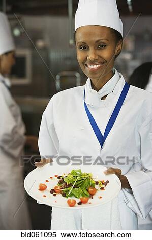 Stock Photography - African female chef holding plate of food. Fotosearch