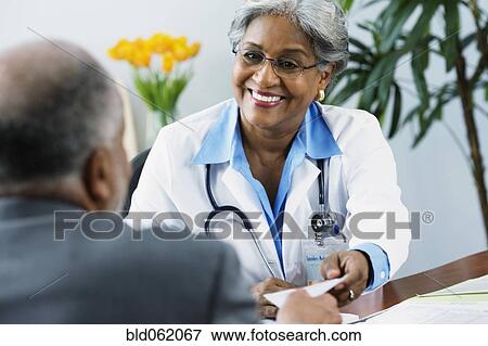 Stock Photo - African female doctor handing prescription to patient. Fotosearch