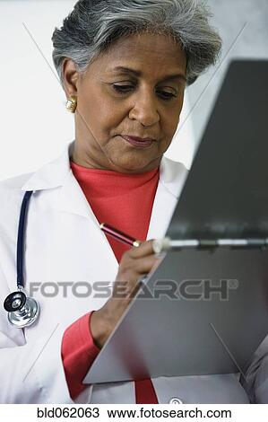 African female doctor writing in medical chart View Large Photo Image Stock Image - African female doctor writing in medical chart. Fotosearch