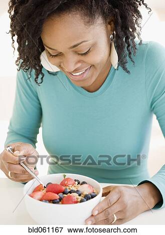 Stock Photo - African woman eating cereal. Fotosearch