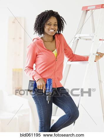 Stock Photography - African woman holding cordless drill. Fotosearch