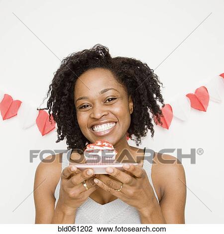 Stock Image - African woman holding cupcake. Fotosearch