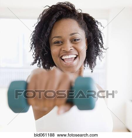 Stock Photo - African woman holding free weight. Fotosearch