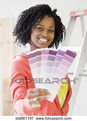 Stock Photo - African woman holding paint swatches. Fotosearch
