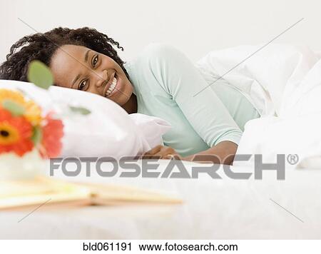 Stock Image - African woman laying in bed. Fotosearch