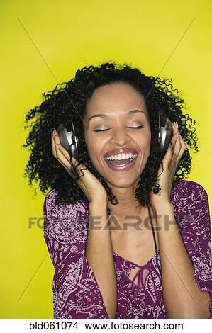 Picture - African woman listening to headphones. Fotosearch