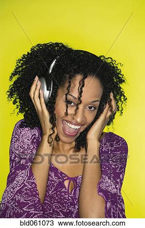 Stock Image - African woman listening to headphones. Fotosearch