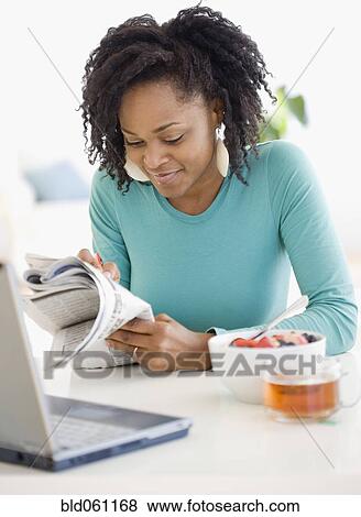 Stock Photo - African woman reading newspaper. Fotosearch