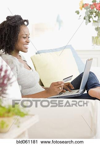Stock Image - African woman shopping online. Fotosearch