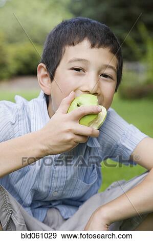 Stock Photo - Asian boy eating apple. Fotosearch