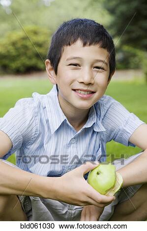 Stock Image - Asian boy holding apple. Fotosearch