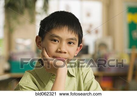 Stock Image - Asian boy with head in hands. Fotosearch