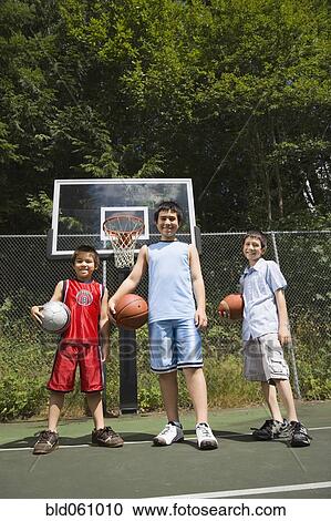 Stock Image - Asian brothers holding basketballs. Fotosearch