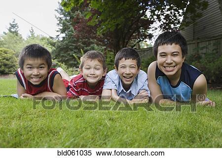 Stock Photography - Asian brothers laying in grass. Fotosearch