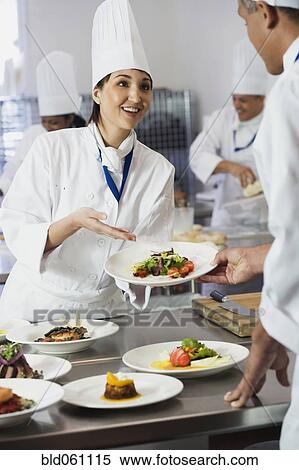 Stock Photography - Asian female chef handing plate of food. Fotosearch
