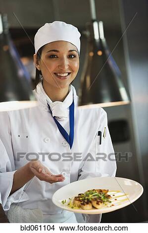 Picture - Asian female chef holding plate of food. Fotosearch
