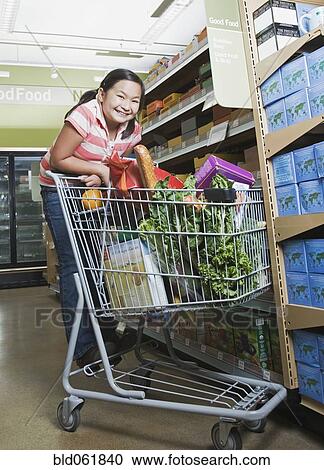 Stock Image - Asian girl grocery shopping. Fotosearch