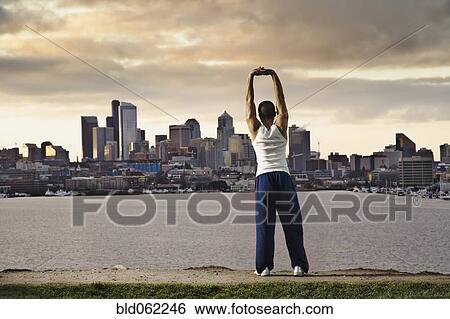 Asian man stretching at urban waterfront View Large Photo Image Stock Photograph - Asian man stretching at urban waterfront. Fotosearch