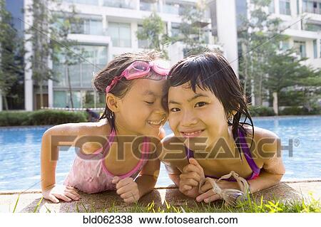 Stock Photo - Asian sisters getting out of swimming pool. Fotosearch