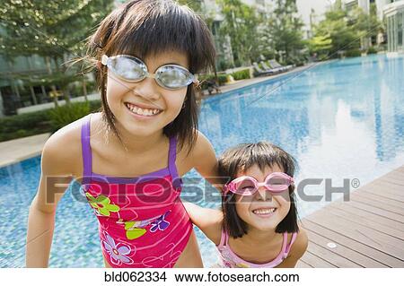 Picture - Asian sisters in goggles at swimming pool. Fotosearch