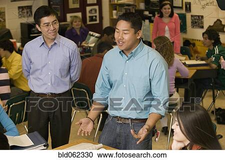 Stock Image - Asian teacher talking to students in classroom. Fotosearch