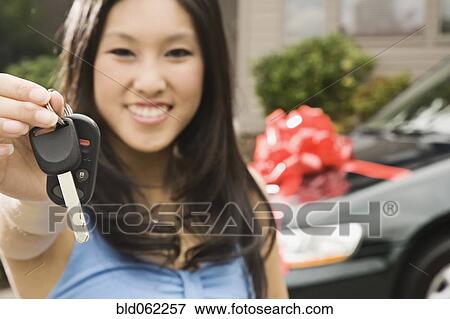 Stock Photo - Asian teenager holding keys to new car. Fotosearch