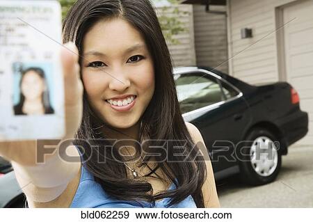 Stock Photo - Asian teenager proudly showing new driver’s license. Fotosearch