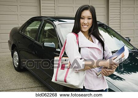 Asian teenager with school books in driveway View Large Photo Image Stock Photo - Asian teenager with school books in driveway. Fotosearch