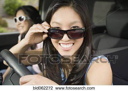 Stock Image - Asian teenagers driving in car. Fotosearch