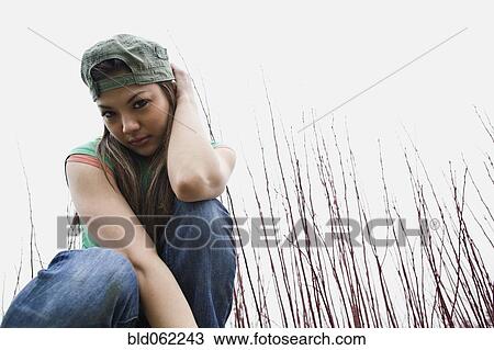 Asian woman kneeling outdoors in grass View Large Photo Image Stock Image - Asian woman kneeling outdoors in grass. Fotosearch