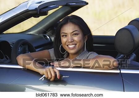 Stock Image - Asian woman sitting in convertible car. Fotosearch