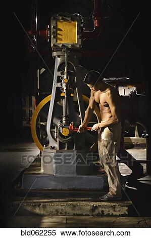 Stock Photography - Bare chested Asian man working in factory. Fotosearch