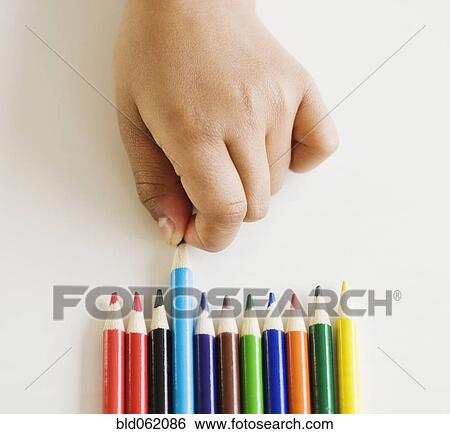 Stock Photograph - Close up of mixed race girl choosing colored pencil. Fotosearch