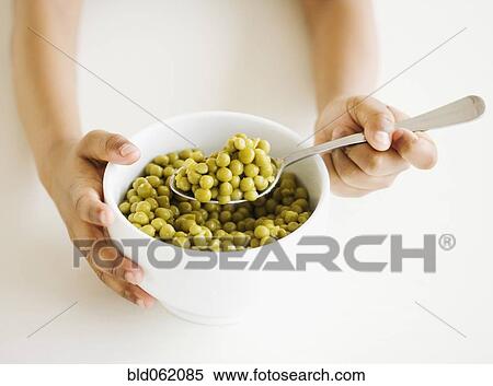 Stock Photography - Close up of mixed race girl eating bowl of peas. Fotosearch
