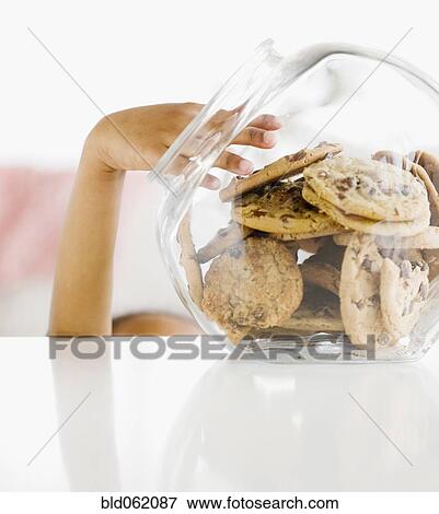 Stock Photo - Close up of mixed race girl taking cookie from jar. Fotosearch