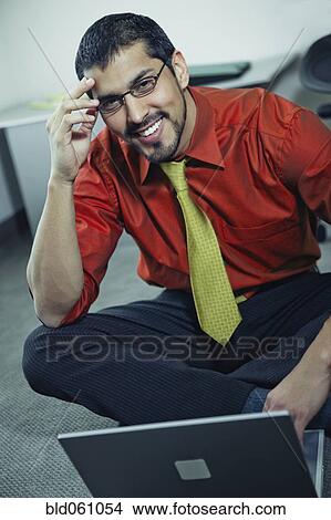 Picture - Hispanic businessman next to laptop. Fotosearch