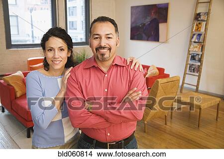 Picture - Hispanic couple standing in livingroom. Fotosearch