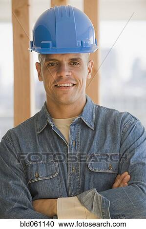 Stock Image - Hispanic male construction worker with arms crossed. Fotosearch