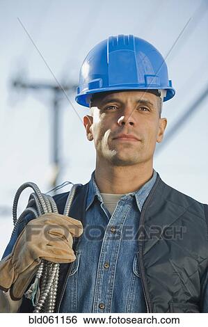 Stock Photograph - Hispanic male electrician carrying coiled wire. Fotosearch