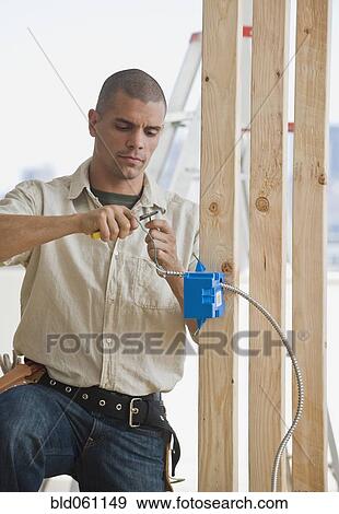 Stock Photo - Hispanic male electrician working in new construction. Fotosearch