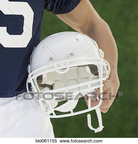 Stock Photography - Hispanic male football player holding helmet. Fotosearch
