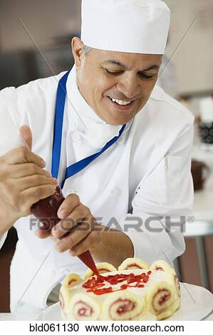 Hispanic male pastry chef decorating cake View Large Photo Image Stock Image - Hispanic male pastry chef decorating cake. Fotosearch