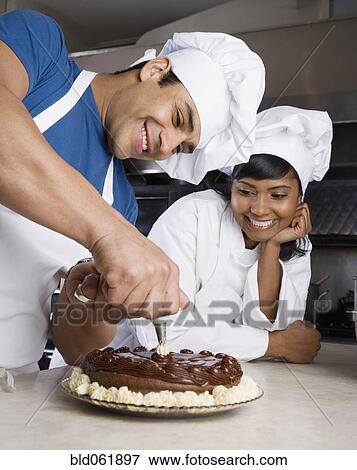 Stock Photo - Hispanic male pastry chef decorating cake. Fotosearch