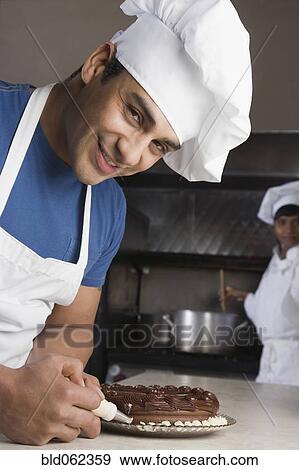 Stock Photo - Hispanic male pastry chef decorating cake. Fotosearch